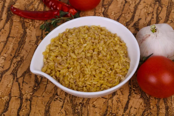 Raw bulgur in the bowl with tomatoes and garlic — Stock Photo, Image