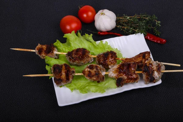 Brochettes de kebab de porc dans l'assiette avec feuilles de salade et tomates — Photo