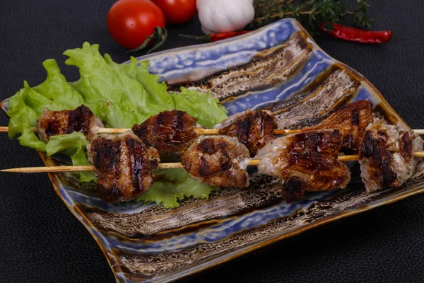 Domuz kebap şişleri plaka salata yaprakları ve domates ile