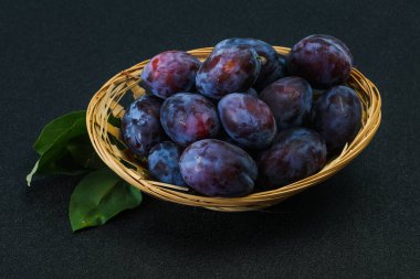 Olgun erik yığını sepetin içinde yapraklarla