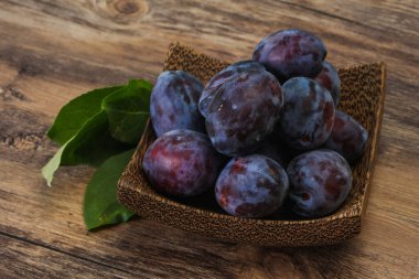 Olgun erik yığını sepetin içinde yapraklarla