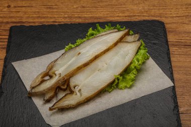 Lezzetli füme halibut balığı aperatifi keser.