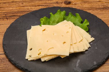 Salata yapraklarının üzerinde dilimlenmiş sarı peynir.