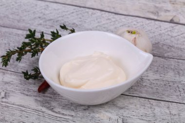 Mayonnaise sauce in the white bowl served thyme, red pepper and garlic clipart