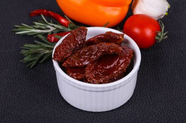 Kavanozda kurutulmuş domates, zeytinyağı biberiye, salata yaprakları ve sarımsak.