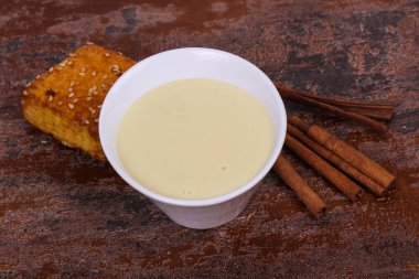 Condenced milk in the bowl with sinnamon sticks and pastry clipart