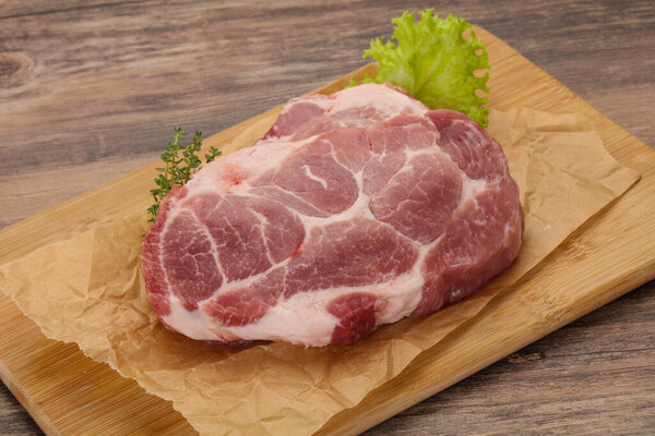 Raw pork steak over wooden board ready for cooking