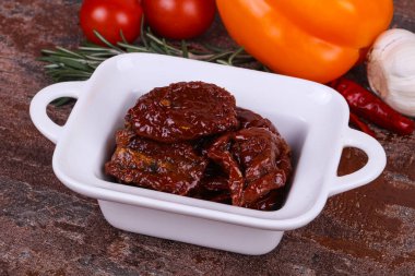 Kavanozda kurutulmuş domates, zeytinyağı biberiye, salata yaprakları ve sarımsak.