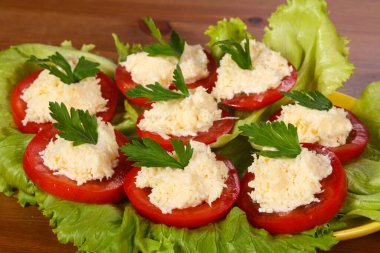 Peynirli domates dilimleri maydanoz ve salata yaprakları.