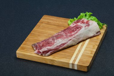 Tahtanın üzerinde çiğ domuz pastırması salata ve kekik servis edildi.