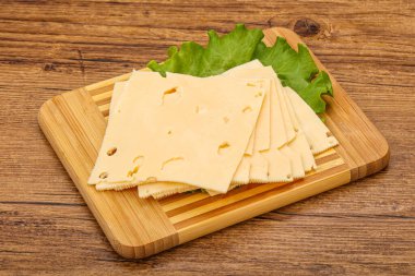 Salata yapraklarının üzerinde dilimlenmiş sarı peynir.