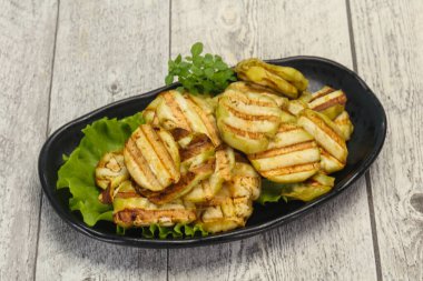 Izgara patlıcan dilimleri fesleğen ve salata yaprakları servis edilir.