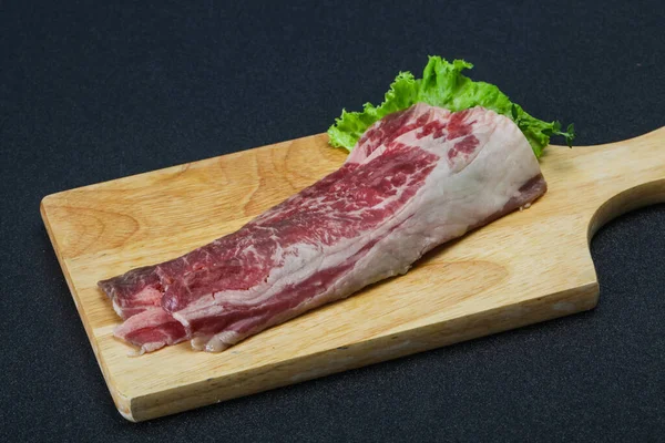 木製ボード上の生の牛肉ベーコンはサラダとタイムを提供 — ストック写真