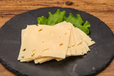 Salata yapraklarının üzerinde dilimlenmiş sarı peynir.