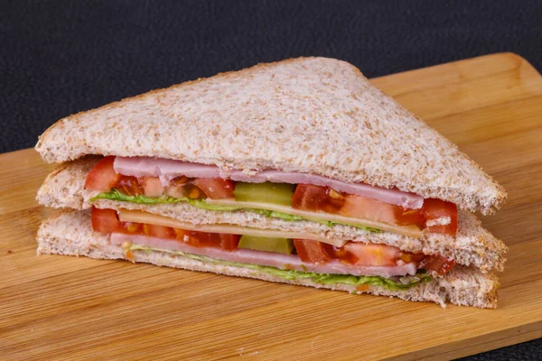 Club sandwich with ham , cheese, salad leaves, tomatoes and pickled cucumbers