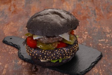 Peynirli ve sebzeli lezzetli siyah hamburger.