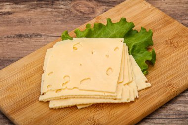 Salata yapraklarının üzerinde dilimlenmiş sarı peynir.