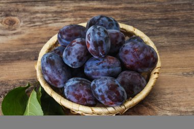 Olgun erik yığını sepetin içinde yapraklarla