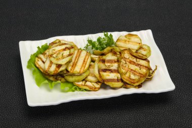 Izgara patlıcan dilimleri fesleğen ve salata yaprakları servis edilir.