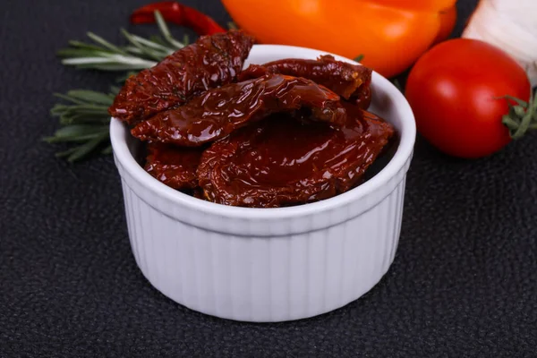 Kavanozda kurutulmuş domates, zeytinyağı biberiye, salata yaprakları ve sarımsak.