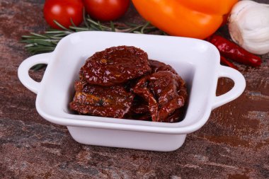 Kavanozda kurutulmuş domates, zeytinyağı biberiye, salata yaprakları ve sarımsak.