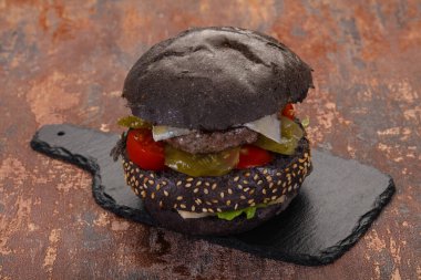 Peynirli ve sebzeli lezzetli siyah hamburger.
