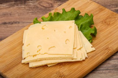 Salata yapraklarının üzerinde dilimlenmiş sarı peynir.