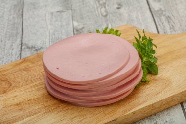 Dilimlenmiş domuz doğal sosisi güvertede fesleğen servis edilir.