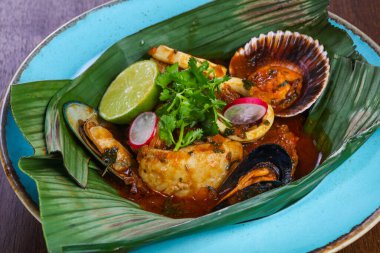 Muz yaprağında Bouillabaisse çorbası, karides ve deniz tarağı.