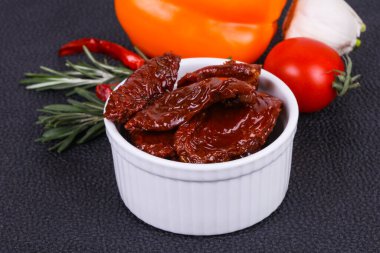 Kavanozda kurutulmuş domates, zeytinyağı biberiye, salata yaprakları ve sarımsak.