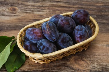 Olgun erik yığını sepetin içinde yapraklarla