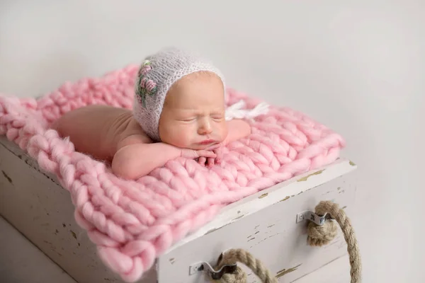 Sleeping newborn baby with chubby cheeks lying in box on rug — Stock Photo, Image