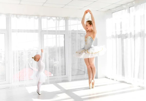 Jonge prachtige ballerina met haar dochtertje dansen in studio — Stockfoto