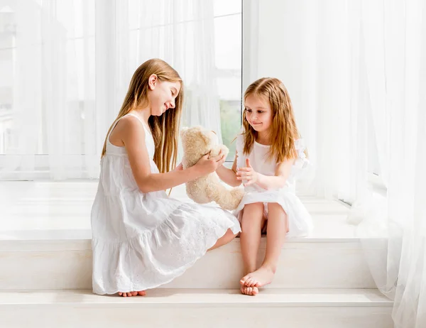 Menina dando seu brinquedo de ursinho de pelúcia para irmã mais velha — Fotografia de Stock