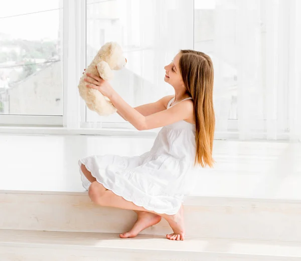 Liittle girl sitting on the floor and holding Teddy bear toy — Stock Photo, Image