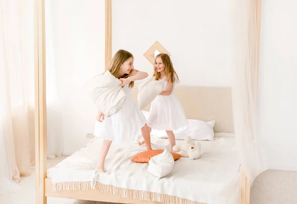 Δύο μικρά κορίτσια αγωνίζονται με μαξιλάρια στο κρεβάτι — Φωτογραφία Αρχείου
