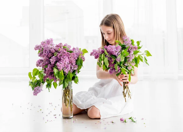 Flicka med bukett lila blommor sittande på golvet — Stockfoto