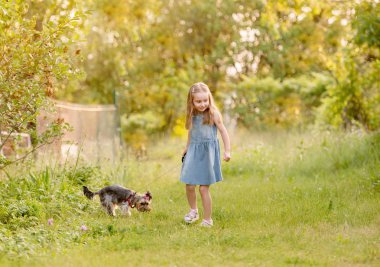 Little girl running with the dog in the countryside clipart