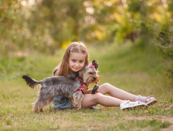 Enfant fille avec son petit chien Yorkshire terrier dans le parc — Photo