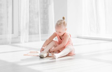 Katta oturan ve pointe ayakkabı bağlama tutu genç bale dansçısı