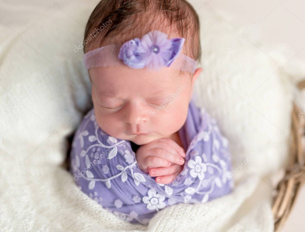 Cute newborn baby girl wrapped in floral cocoon