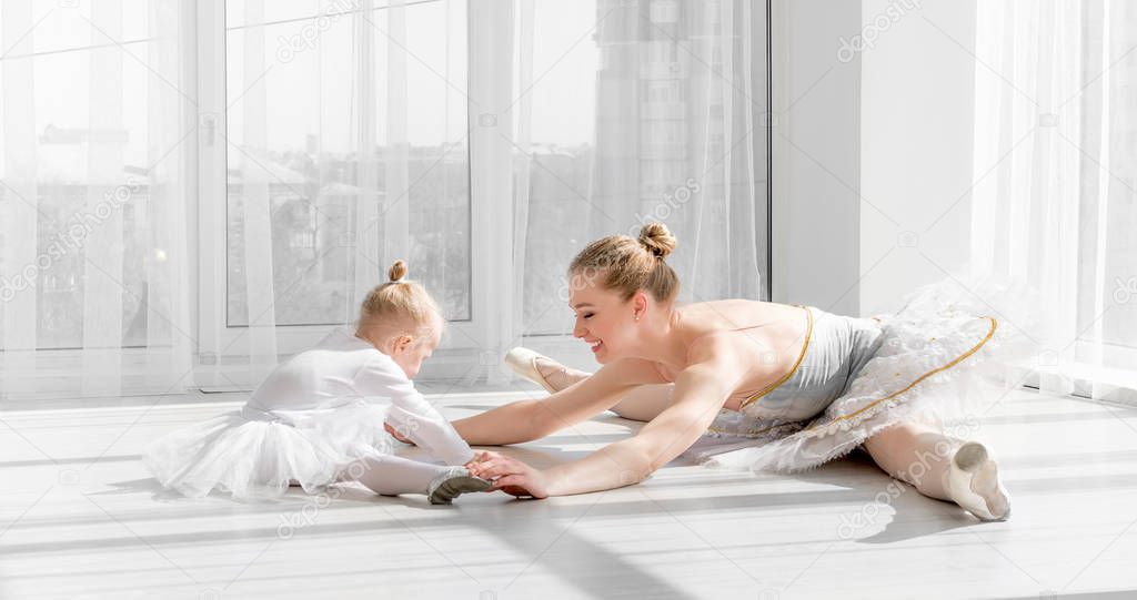 Ballerina with child girl warming up before training
