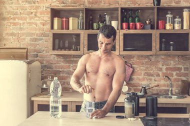 atletik adam limon suyuyla mutfakta yapar.