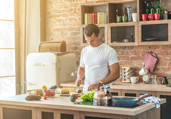 Homme dans la cuisine coupe une baguette — Photo