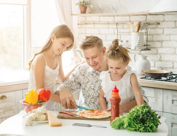 dad with daughters preparing pizza