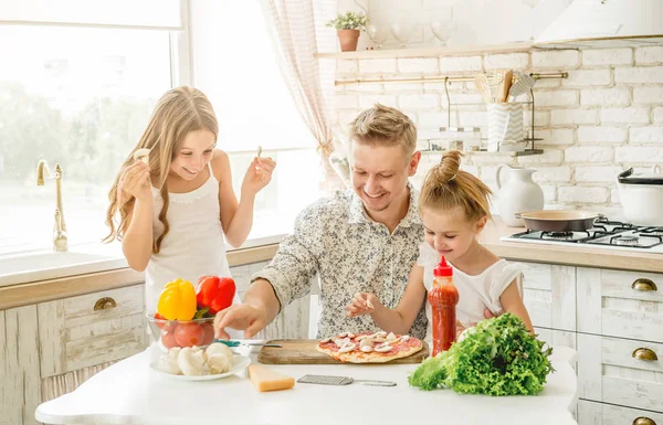 dad with daughters preparing pizza