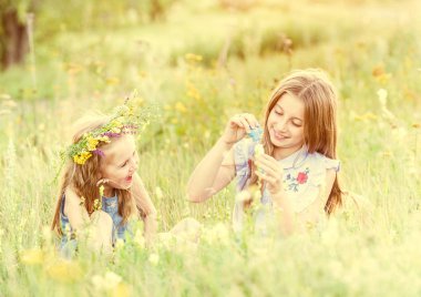 İki küçük kız kardeşi sabun köpüğü üfleme