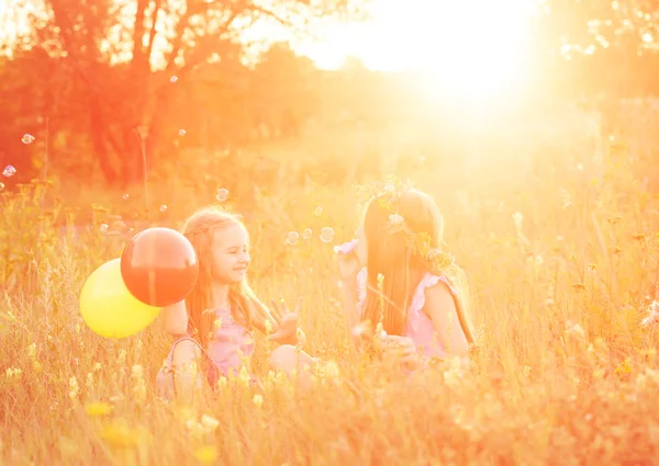 Two little sisters blowing soap bubbles — Stock Photo, Image