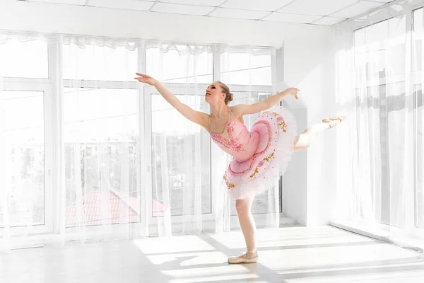 Элегантная балетная танцовщица в розовой пачке, практикующая и улыбающаяся — стоковое фото