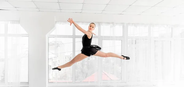 Балерина танцует прыжок в белой студии — стоковое фото
